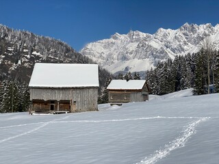 Indigenous alpine huts and wooden cattle stables on Swiss pastures covered with fresh white snow cover, Nesslau - Obertoggenburg, Switzerland (Schweiz)