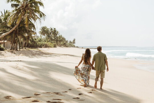 Couple in love walking along the beach under palm trees