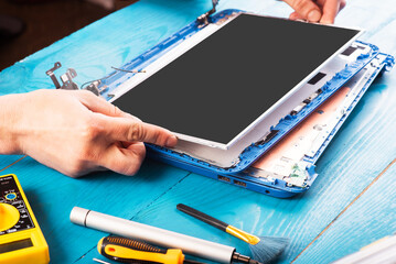 Wizard repairs laptop with tools and hands on the blue wooding table. top view