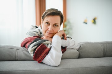 Mature Woman. Beautiful Healthy Middle Age Female Sitting On Sofa At Home. Beauty And Comfort Concept.