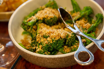 broccoli in bowl with silverware and crumbs low light with grain and out of focus