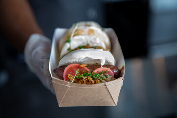Boa bun with sausage pickles and micro greens out of focus with grain