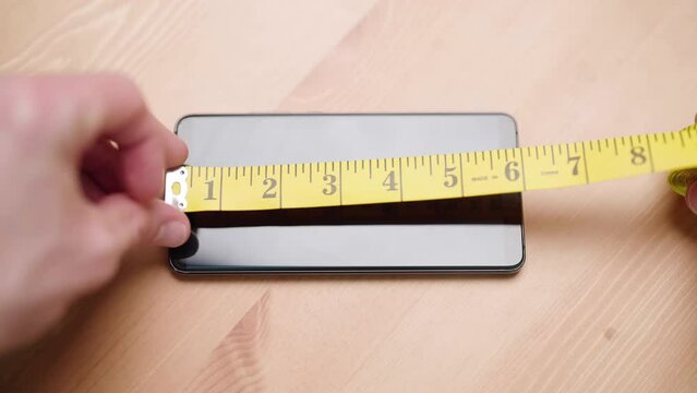 Person with measuring tape measure size of smartphone on table 4K