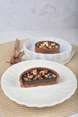 luxury home baked rocher dark rich chocolate tart in 3 layer with hazelnut mixed nuts and gold foil in white background halal dessert menu for hotel cafe