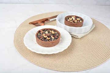 luxury home baked rocher dark rich chocolate tart in 3 layer with hazelnut mixed nuts and gold foil in white background halal dessert menu for hotel cafe
