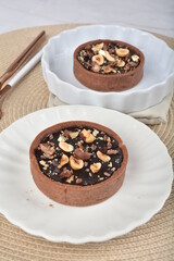luxury home baked rocher dark rich chocolate tart in 3 layer with hazelnut mixed nuts and gold foil in white background halal dessert menu for hotel cafe