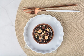 luxury home baked rocher dark rich chocolate tart in 3 layer with hazelnut mixed nuts and gold foil in white background halal dessert menu for hotel cafe