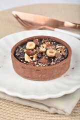 luxury home baked rocher dark rich chocolate tart in 3 layer with hazelnut mixed nuts and gold foil in white background halal dessert menu for hotel cafe