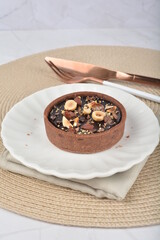 luxury home baked rocher dark rich chocolate tart in 3 layer with hazelnut mixed nuts and gold foil in white background halal dessert menu for hotel cafe