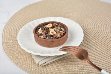 luxury home baked rocher dark rich chocolate tart in 3 layer with hazelnut mixed nuts and gold foil in white background halal dessert menu for hotel cafe