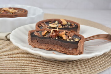 luxury home baked rocher dark rich chocolate tart in 3 layer with hazelnut mixed nuts and gold foil in white background halal dessert menu for hotel cafe