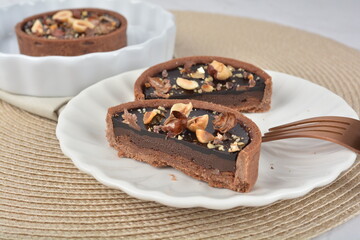 luxury home baked rocher dark rich chocolate tart in 3 layer with hazelnut mixed nuts and gold foil in white background halal dessert menu for hotel cafe
