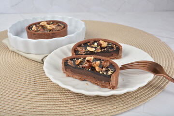 luxury home baked rocher dark rich chocolate tart in 3 layer with hazelnut mixed nuts and gold foil in white background halal dessert menu for hotel cafe