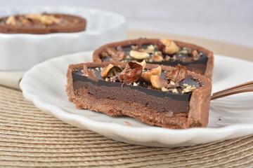 luxury home baked rocher dark rich chocolate tart in 3 layer with hazelnut mixed nuts and gold foil in white background halal dessert menu for hotel cafe