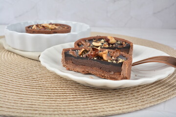 luxury home baked rocher dark rich chocolate tart in 3 layer with hazelnut mixed nuts and gold foil in white background halal dessert menu for hotel cafe