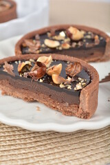 luxury home baked rocher dark rich chocolate tart in 3 layer with hazelnut mixed nuts and gold foil in white background halal dessert menu for hotel cafe