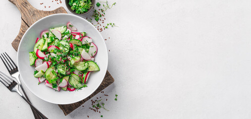 Healthy, summer salad with radish, cucumber, fresh herbs on a light gray background. Top view, copy space.