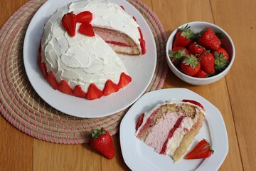 Cut Zuccotto, traditional italian dome shaped cake with white chocolate  and strawberries cream on wooden table. Charlotte cake with strawberries