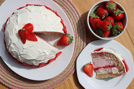 Cut Zuccotto, traditional italian dome shaped cake with white chocolate  and strawberries cream on wooden table. Charlotte cake with strawberries