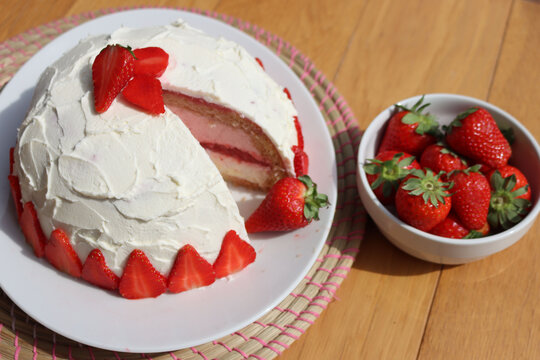 Cut Zuccotto, traditional italian dome shaped cake with white chocolate  and strawberries cream on wooden table. Charlotte cake with strawberries