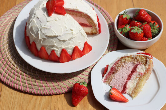 Cut Zuccotto, traditional italian dome shaped cake with white chocolate  and strawberries cream on wooden table. Charlotte cake with strawberries