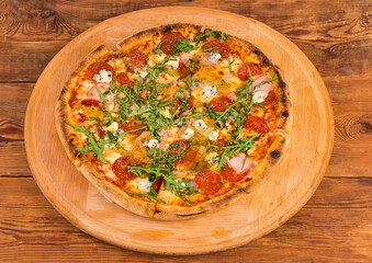 Pizza with meat products on the round wooden pizza board