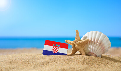 Fototapeta na wymiar Tropical beach with seashells and Croatian flag. The concept of a paradise vacation on the beaches of Croatia.