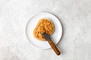 Toast with Peanut butter. Smearing Sweet Peanut butter sauce on bread with knife. Top view.