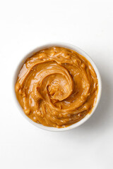 Peanut butter in a white saucer on white background. Curl of Peanut butter. Top view.