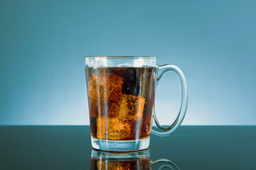 cola with ice in a glass bottle on blue background.