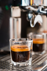 Pouring coffee stream from professional machine in cup. Barista man making espresso shot by bottomless, using filter holder. Flowing fresh ground coffee. Drinking roasted black coffee in the morning.