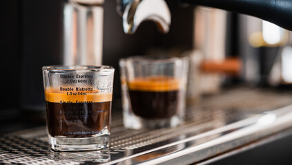 Pouring coffee stream from professional machine in cup. Barista man making espresso shot by bottomless, using filter holder. Flowing fresh ground coffee. Drinking roasted black coffee in the morning.