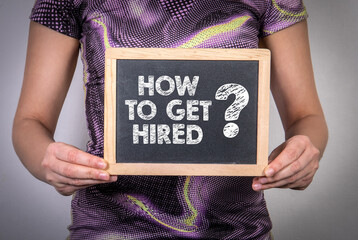 How To Get Hired. Woman holding a chalk board - Powered by Adobe