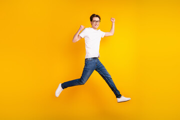 Obraz na płótnie Canvas Full body photo of young man jump up run rejoice winner fists hands triumph isolated over yellow color background
