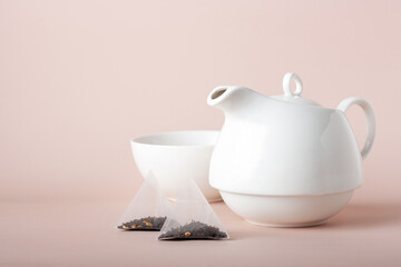 triangular tea bags on white ceramic tableware background, copy space, selective focus