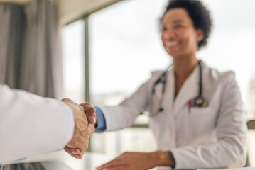 Smiling female doctor shaking hands with patient at hospital