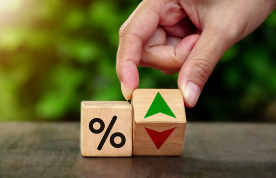 The concept of changing interest rates in banks falling and rising. Hand flip wood cube change arrow down to up. nature background.  