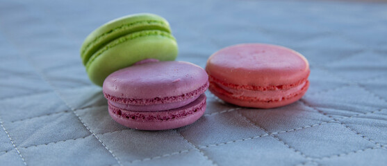 Macarons three cookies on a cloth napkin background. Multicolored french pasta for breakfast.