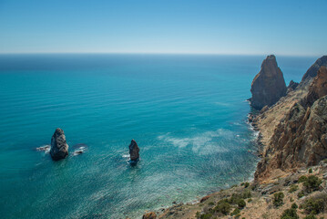 Top view of the rocky coast of the sea with turquoise water. Rocks stick out of the water