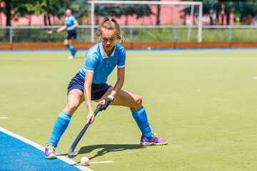 Young woman field hockey player performing corner penalty.
