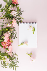 vertical top view of the blank white sheets of the notebook. pink pastel background with spring flowers. An empty layout for text.