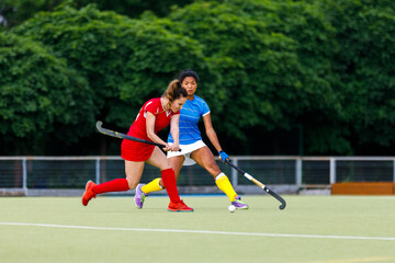 Young woman field hockey player leading the ball in attack.