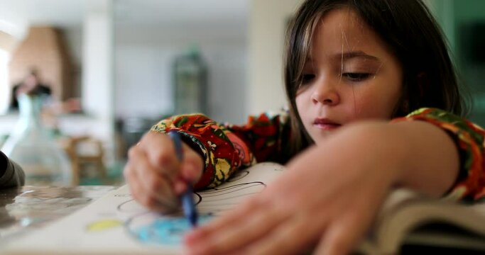 Little girl drawing on paper child draws with color crayon