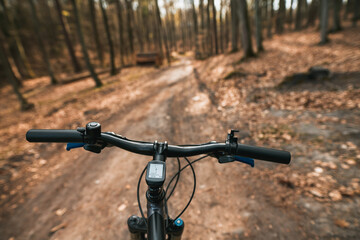 Fototapeta na wymiar Top view of mountain bike handlebar and blurred cross country forest road. Concept of extreme activity on the woods trails.