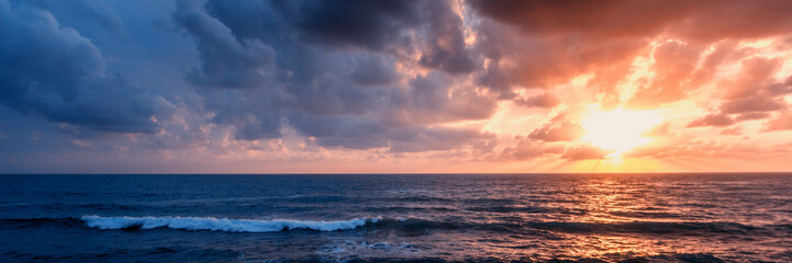 Obraz premium Bright beautiful stunning sea sunset, waves beating against the rocks and the sun