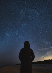Man stargazing and exploring Milky Way Galaxies. Long exposure photo of a night sky full of stars with the silhouette of a human with no face. Concept of young people dreaming about a bright future.