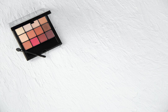 The eyeshadow palette lies in the upper left corner on a white textured background. High quality photo