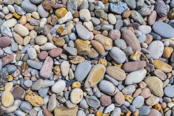 Pebble beach background, small colored rounded stones on a sea shore