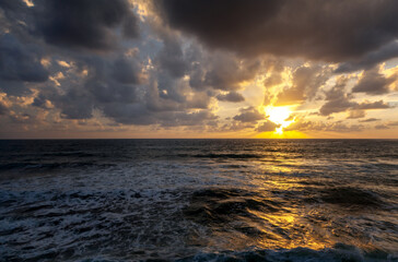 Bright beautiful stunning sea sunset, waves beating against the rocks in the rays of the setting sun