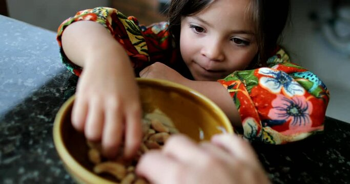 Little girl eating cashew nuts from bowl child eats healthy snack food